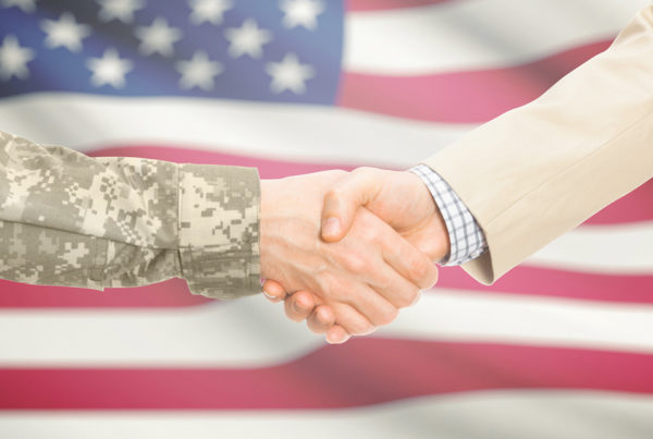 Shaking hands in front of American flag.