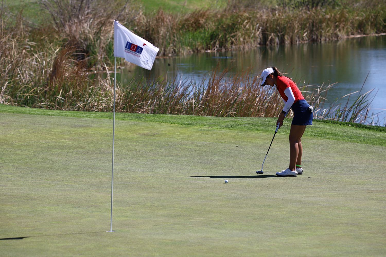 Golfer hitting golf ball close to flag